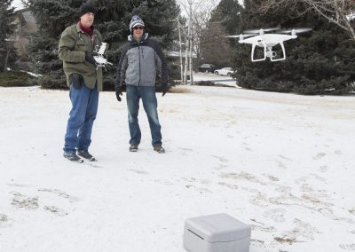 Two men flying drone in snowy park.