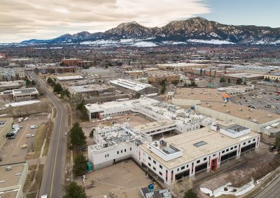 Aerial view of city below snowy mountains.